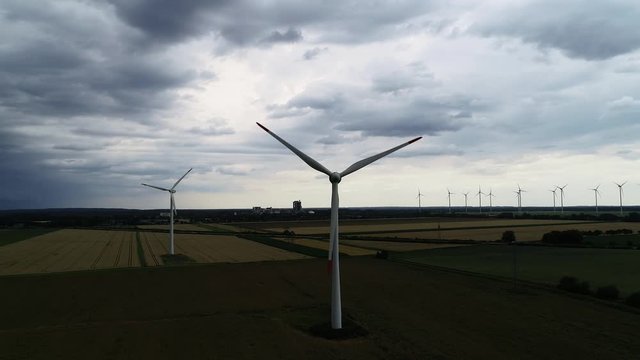Drohne fliegt an Windkraftanlage vorbei w&auml;hrend eines Unwetters