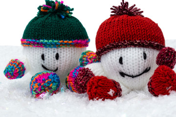 Snowballs knitted Christmas decorations with hat and scarf on artificial snow. With a white background