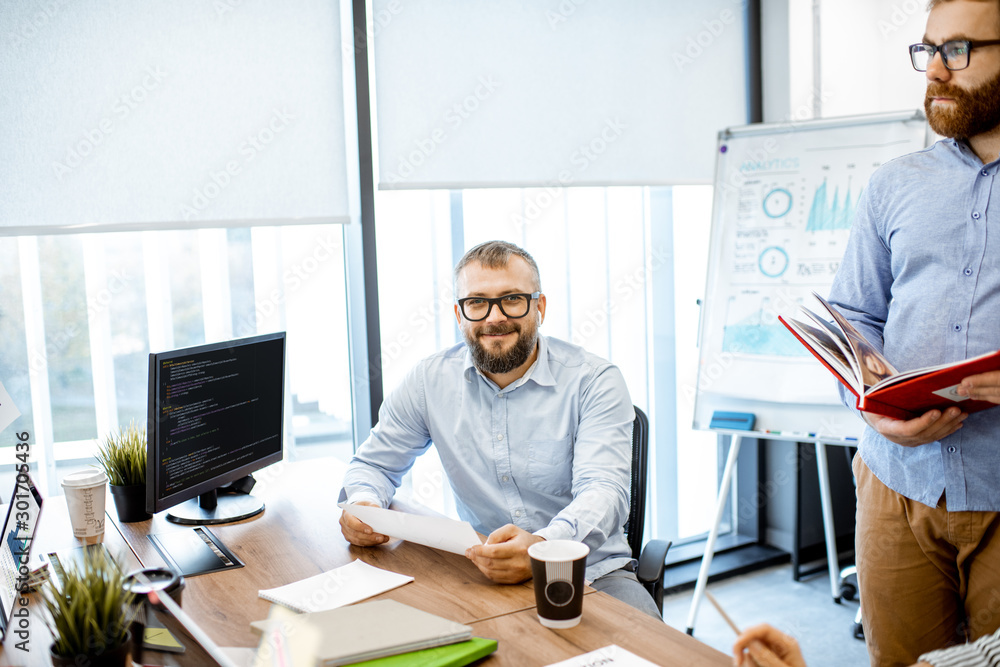 Wall mural portrait of a handsome bearded office worker dressed casually during a work in the office