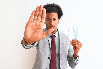 Young african american businessman holding boarding pass over isolated white background with open hand doing stop sign with serious and confident expression, defense gesture