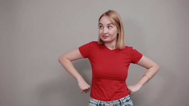Attractive woman in red shirt posing isolated on grey wall background studio portrait, looking at camera smile. People sincere emotions lifestyle concept