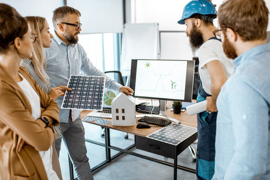 Group Of Alternative Energy Engineers Discussing A Project With A Worker During A Meeting In The Office. Green Energy Development Concept