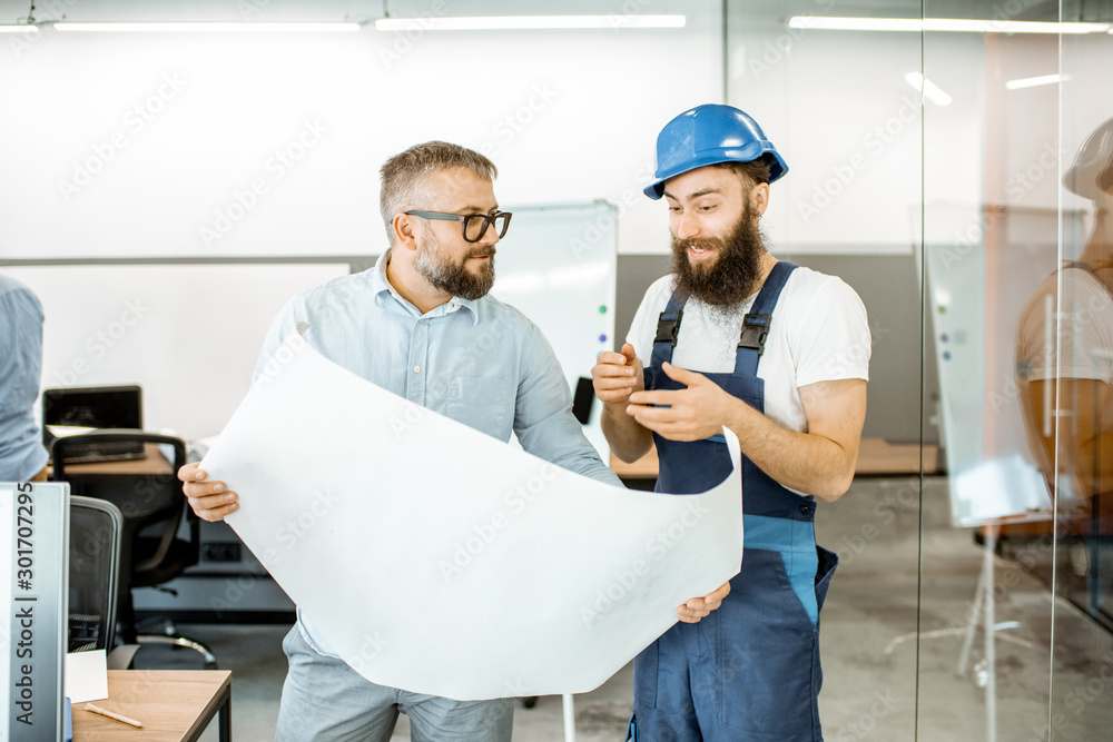 Wall mural senior foreman and workman in overalls working on project with blueprints in the office