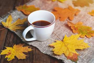coffee cup and autumn fall leaves on wooden background