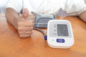 Asian male is checking blood pressure and heart rate with digital pressure gauge