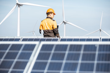 Engineer in protective workwear carrying out service of solar panels with digital tablet on a...