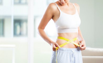 Young woman measuring her waistline