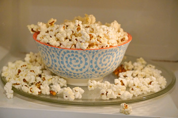 colored plate with popcorn in the microwave, cook with microwaves. popcorn spilled from the plate. exploding corn kernels.