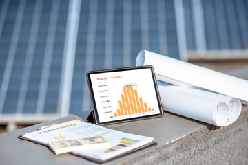 Composition of blueprints, money and digital tablet with a chart of electricity production on a...