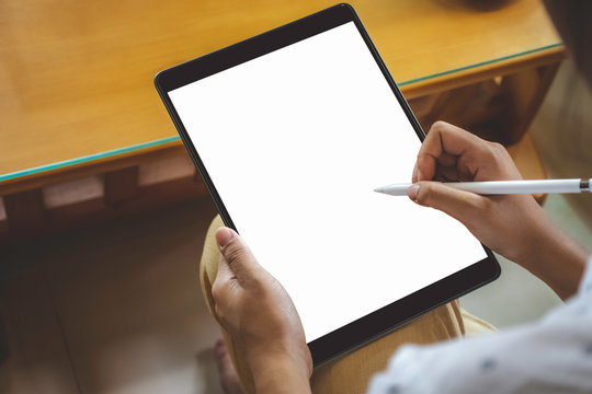 Mockup image of business woman hand holding black tablet computer pc  with blank white screen and using pencil for writing or drawing on it. Top view.