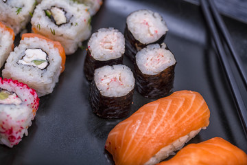 Japanese sushi and rolls with soy sauce and ginger. On a black rustic background
