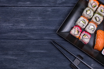 Japanese sushi and rolls with soy sauce and ginger. On a black rustic background