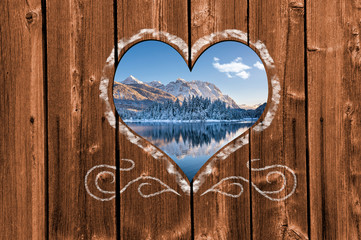 Looking through a carved heart in a wooden wall to beautiful snow covered landscape