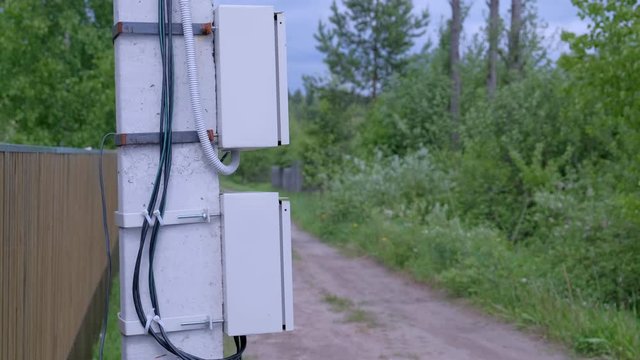 Electric shield on a street pole in the private sector, closeup view. Electric pole on a country road in the village near the fence. Modern equipment for wiring in country houses.