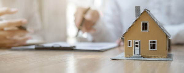 House model with agent and customer discussing for contract to buy, get insurance or loan real...