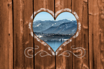 Looking through a carved heart in a wooden wall to beautiful snow covered landscape