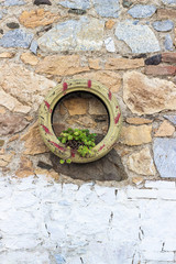 Front shoot of masonry stone wall hanged green colored painted tyre