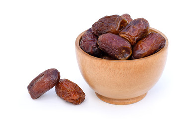 Closeup date palm fruits in wooden bowl isolated on wood table background. Top view.