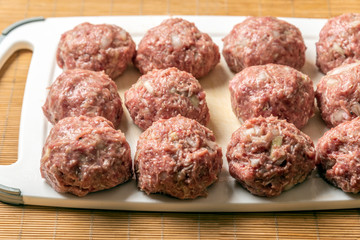 Raw balls of ground beef with spices for the preparation of hamburgers, meatballs.