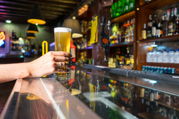 Drunk Wife hand having a meeting in a nightclub on a bar while hold a glass of lager beer with froth. Lady Customer ordering a draft in a pub with nobody. Alcoholic drink while relaxing