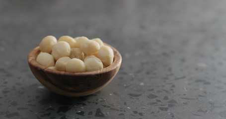 shelled macadamia nuts in olive wood bowl on terrazzo surface
