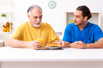 Young male doctor visiting old patient at home