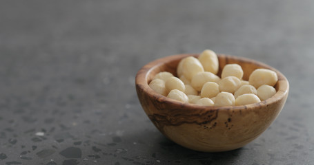 Fototapeta na wymiar shelled macadamia nuts in olive wood bowl on terrazzo surface