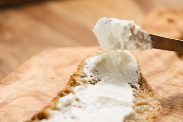 spreading ricotta cheese on fresh rustic bread