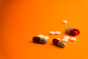 Pills, tablets and bottle on orange background. Copy space for text