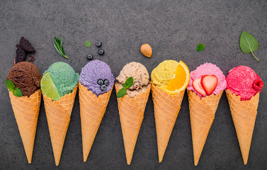 Various of ice cream flavor in cones blueberry ,lime ,pistachio ,almond ,orange ,chocolate ,vanilla and coffee set up on dark stone background . Summer and Sweet menu concept.