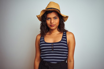 Beautiful transsexual transgender woman wearing summer hat over isolated white background with serious expression on face. Simple and natural looking at the camera.