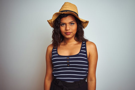 Beautiful transsexual transgender woman wearing summer hat over isolated white background with serious expression on face. Simple and natural looking at the camera. - Powered by Adobe