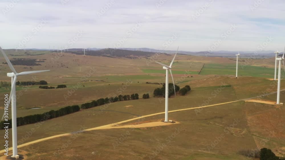 Wall mural aerial view of an array of large wind turbines rotating to create kinetic energy for renewable energ
