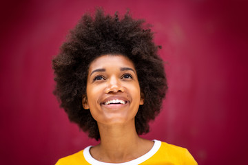 Close up front of beautiful young black woman with afro hairstyle smiling and looking up