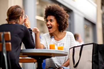 two happy young woman sitting at outdoor cafe together