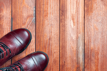 Leather winter boots made of genuine leather stand on a wooden floor. View from above