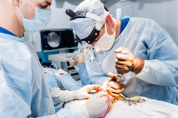 Spinal surgery. Group of surgeons in operating room with surgery equipment. Laminectomy