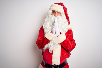Middle age handsome man wearing Santa costume standing over isolated white background praying with hands together asking for forgiveness smiling confident.