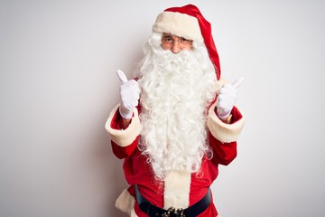 Middle age handsome man wearing Santa costume standing over isolated white background success sign doing positive gesture with hand, thumbs up smiling and happy