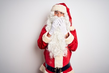 Middle age handsome man wearing Santa costume standing over isolated white background laughing and embarrassed giggle covering mouth with hands, gossip and scandal concept