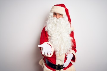 Middle age handsome man wearing Santa costume standing over isolated white background smiling cheerful offering palm hand giving assistance and acceptance.