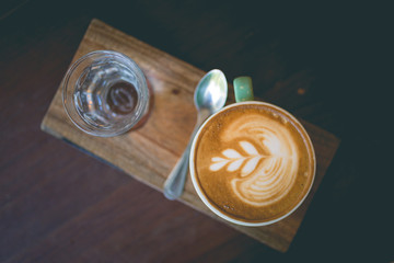 Latte hot coffee with foam milk art on a wooden table