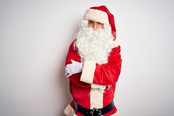 Middle age handsome man wearing Santa costume standing over isolated white background skeptic and nervous, disapproving expression on face with crossed arms. Negative person.