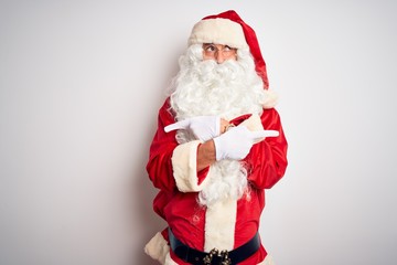 Middle age handsome man wearing Santa costume standing over isolated white background Pointing to both sides with fingers, different direction disagree