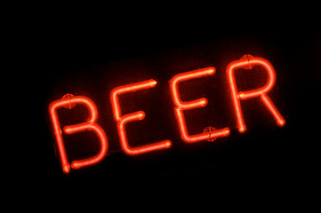 Close up of red neon BEER light in capital  letters outside a bar at night