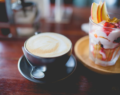 cup of coffee and homemade fruit yoghurt with strawberry jam, apple and conflake
