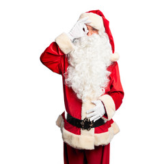 Middle age handsome man wearing Santa Claus costume and beard standing doing ok gesture with hand smiling, eye looking through fingers with happy face.
