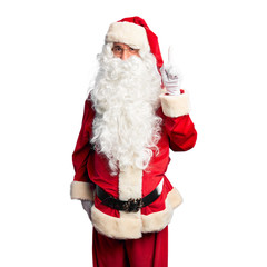 Middle age handsome man wearing Santa Claus costume and beard standing pointing finger up with successful idea. Exited and happy. Number one.