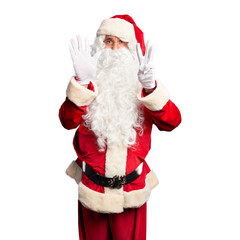 Middle age handsome man wearing Santa Claus costume and beard standing showing and pointing up with fingers number eight while smiling confident and happy.