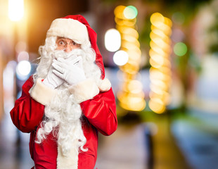 Fototapeta na wymiar Middle age handsome man wearing Santa Claus costume and beard standing shocked covering mouth with hands for mistake. Secret concept.